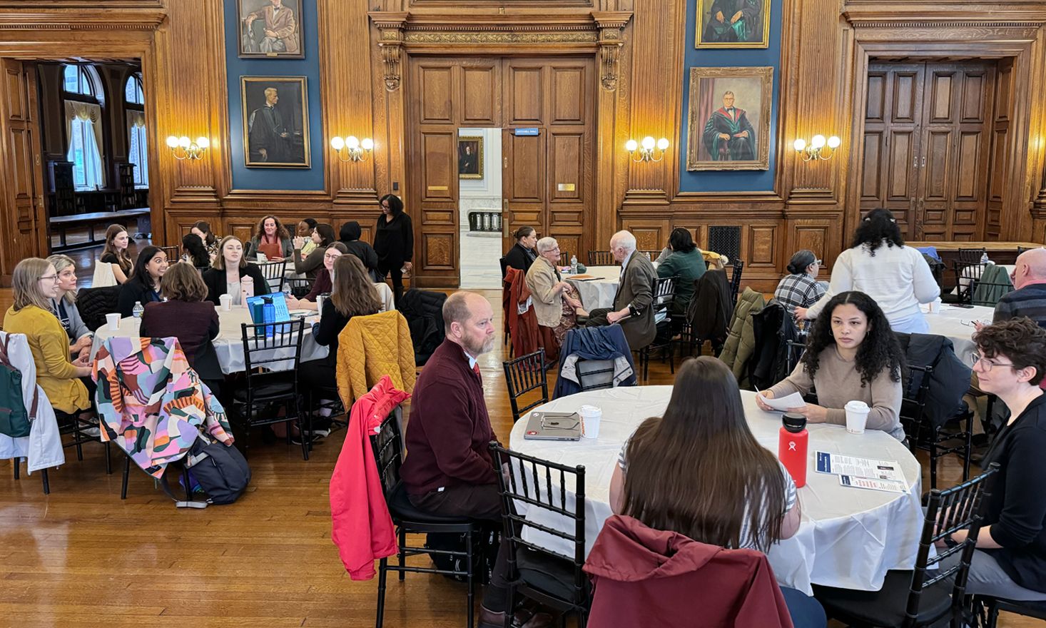Groups of people scattered across several tables in a large room