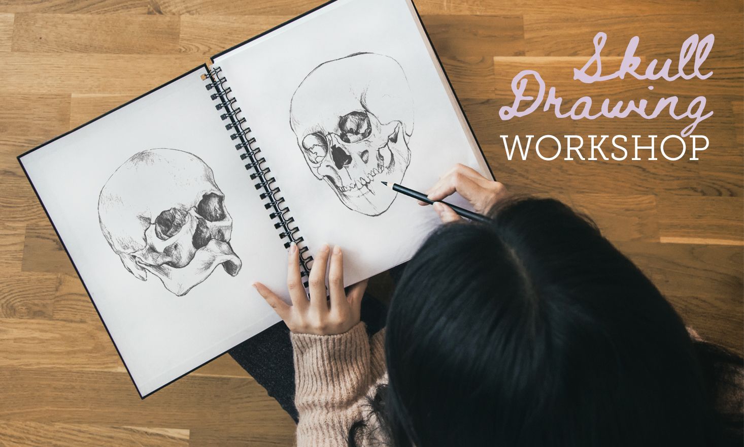 Overhead photo of someone sketching two skulls in an open notebook